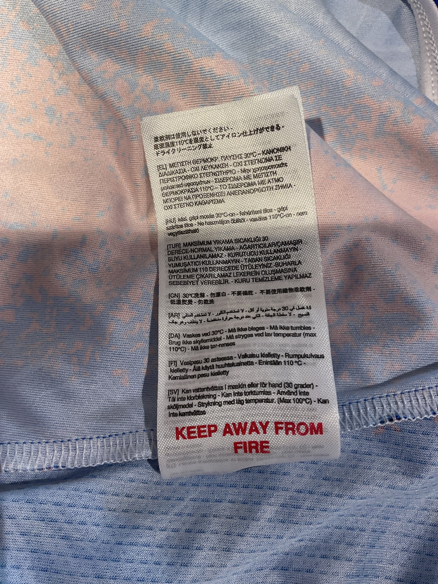 Textile label on a blue fabric background with warning text.