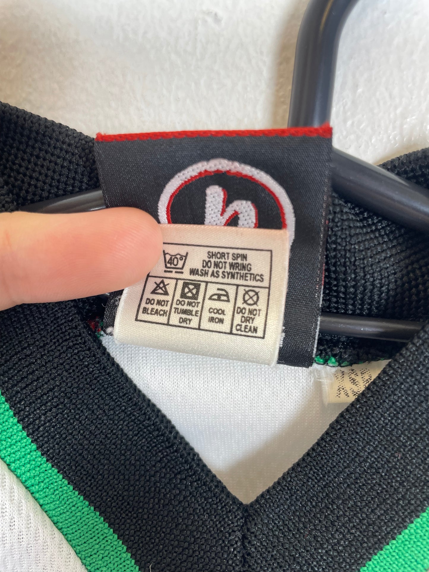 Close-up of the Rochdale AFC club crest and Uhlsport logo on the kids home football shirt, shown in close detail