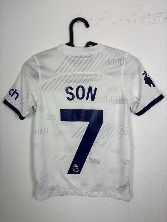 Front view of the Tottenham 23/24 kids home shirt showing the Spurs crest and Nike swoosh, shown in full front detail