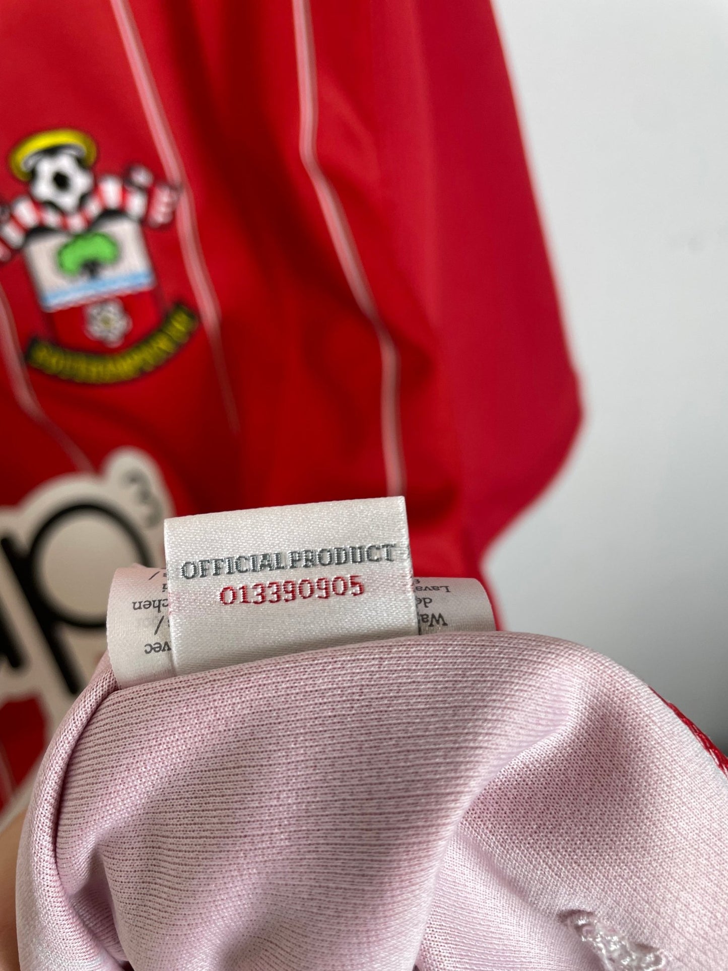 Close-up of the Southampton club crest on the 12/13 red and white striped home shirt, detail shot from our store