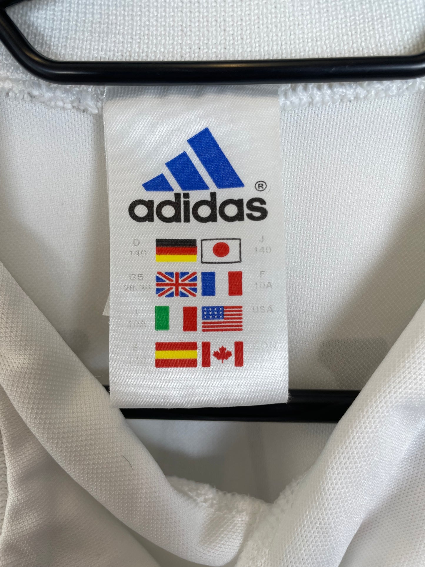 Close-up of Real Madrid club crest and Adidas three stripes on white 01/02 home jersey