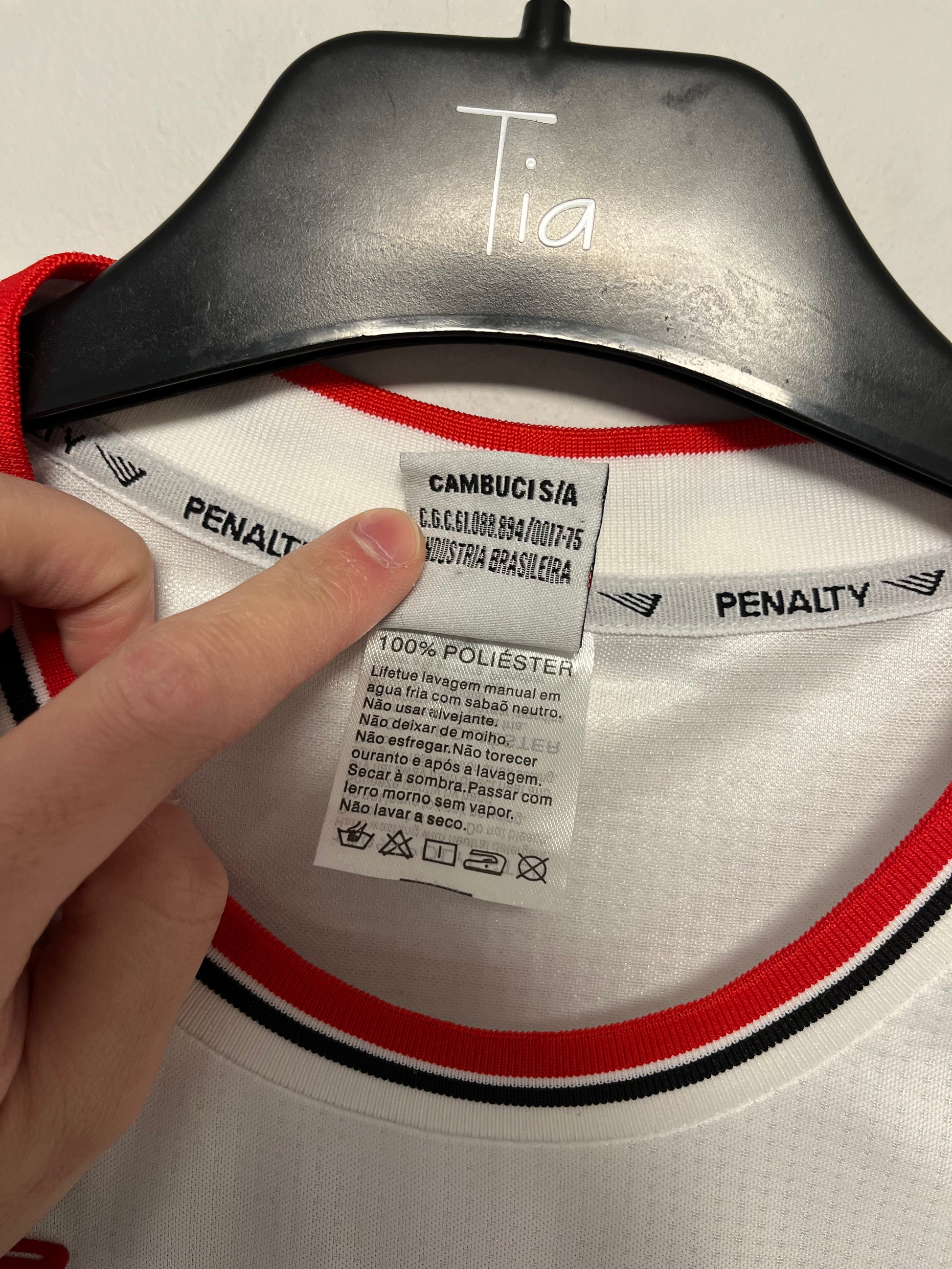 Close-up of a label on a football 2000s jersey with a hand pointing to it.