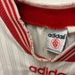Close-up of Adidas label and logo on a retro jersey with red and white details.