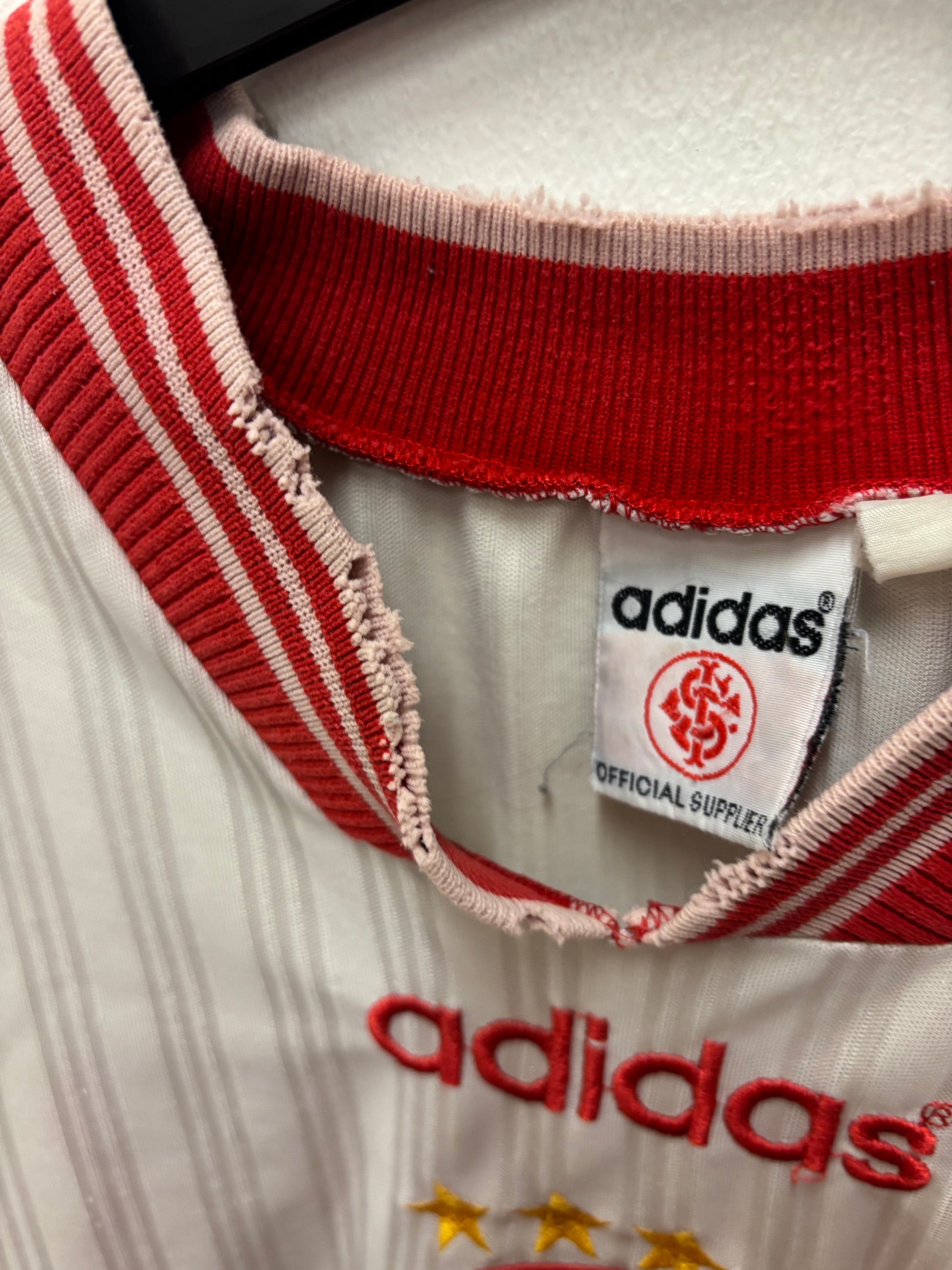 Close-up of Adidas label and logo on a retro jersey with red and white details.