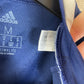 Close-up of a blue Adidas Scottish football team  with a tag showing size and brand details.hirt