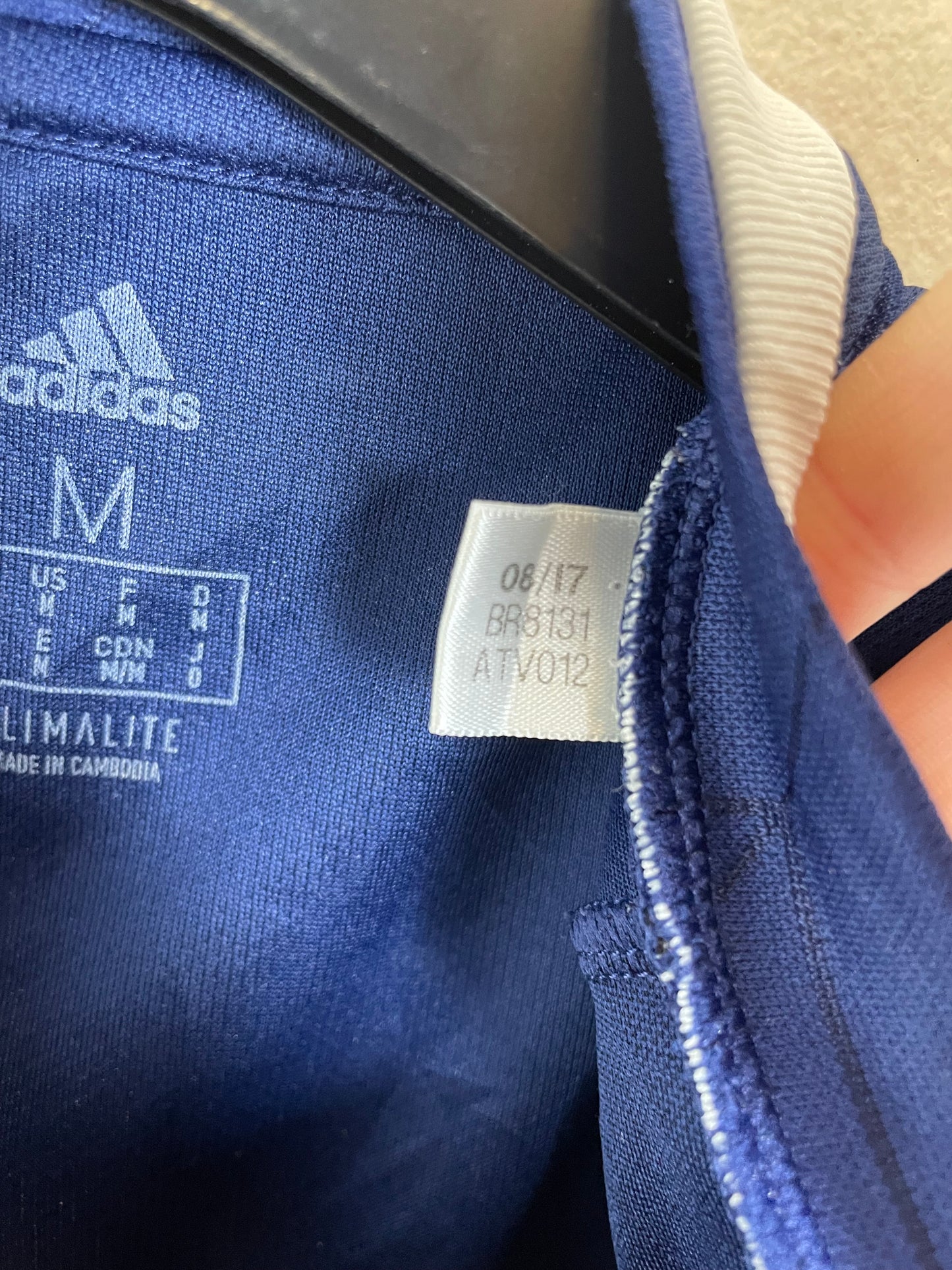 Close-up of a blue Adidas Scottish football team  with a tag showing size and brand details.hirt