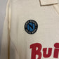 Close-up of a beige napoli shirt with a logo and text on a gray background