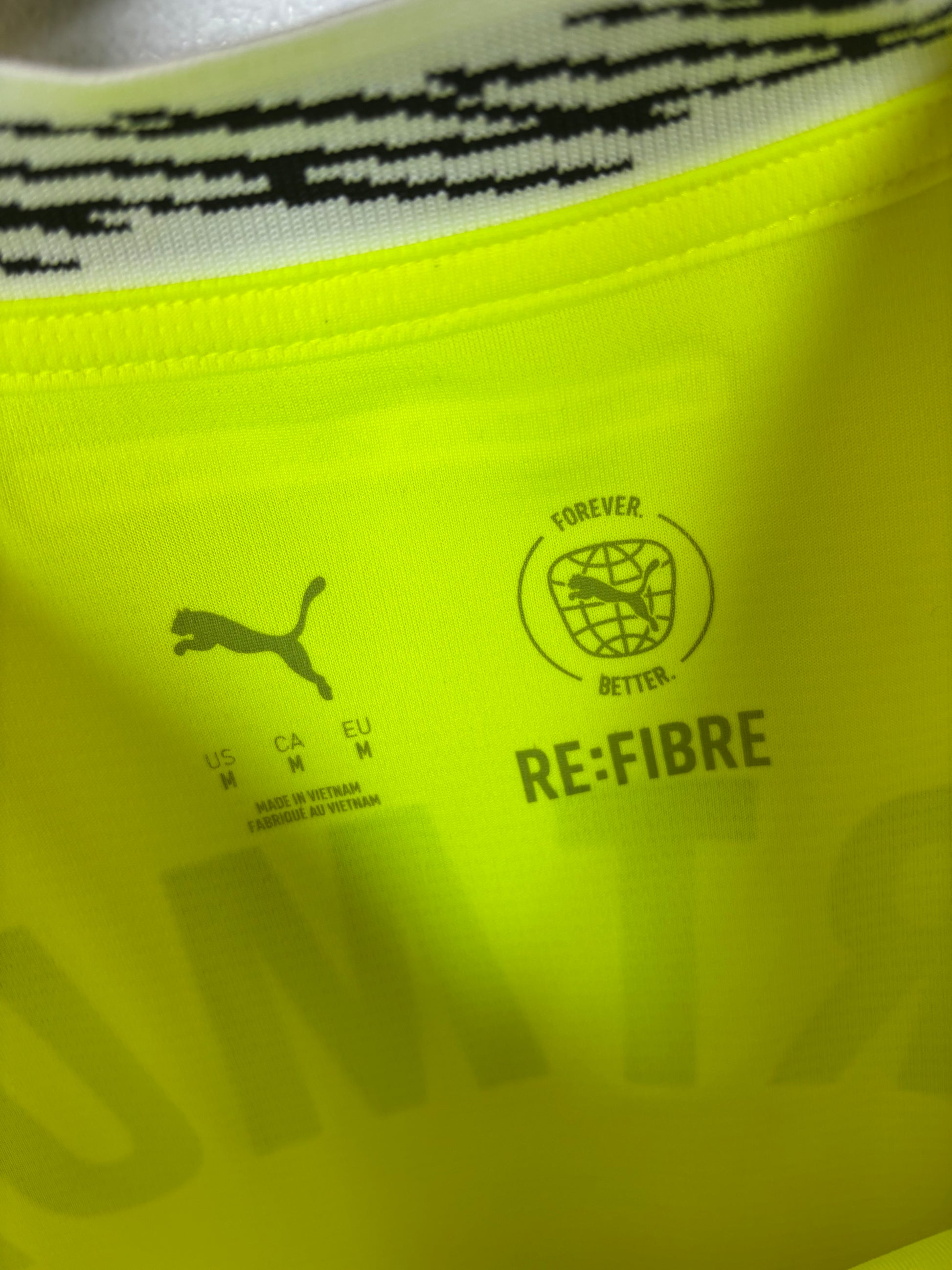 Close-up of Borussia Dortmund club badge and Puma logo on yellow 2024/25 home jersey
