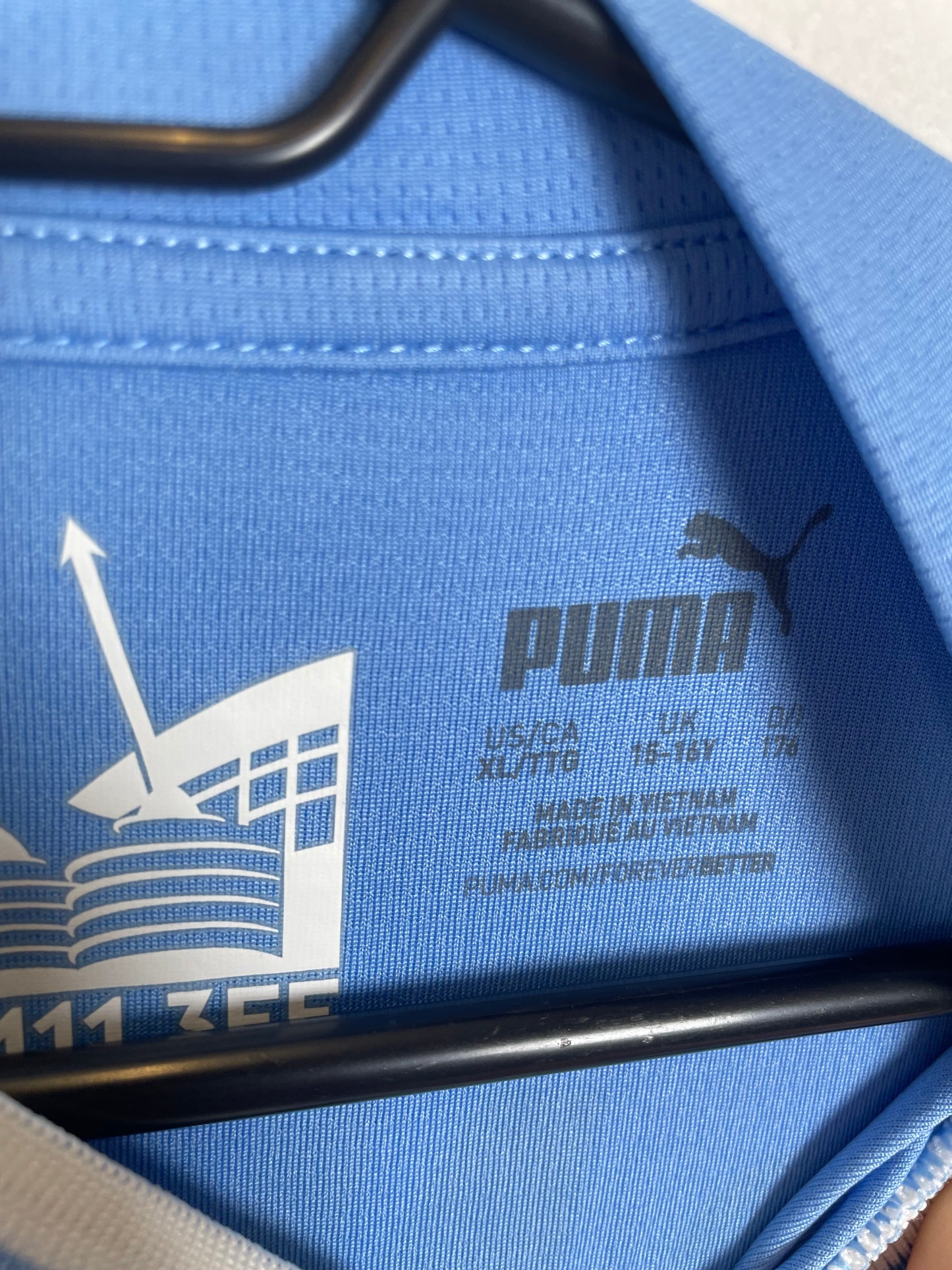 Close-up of Manchester City club badge and sponsor logo on sky blue 2023/24 home shirt
