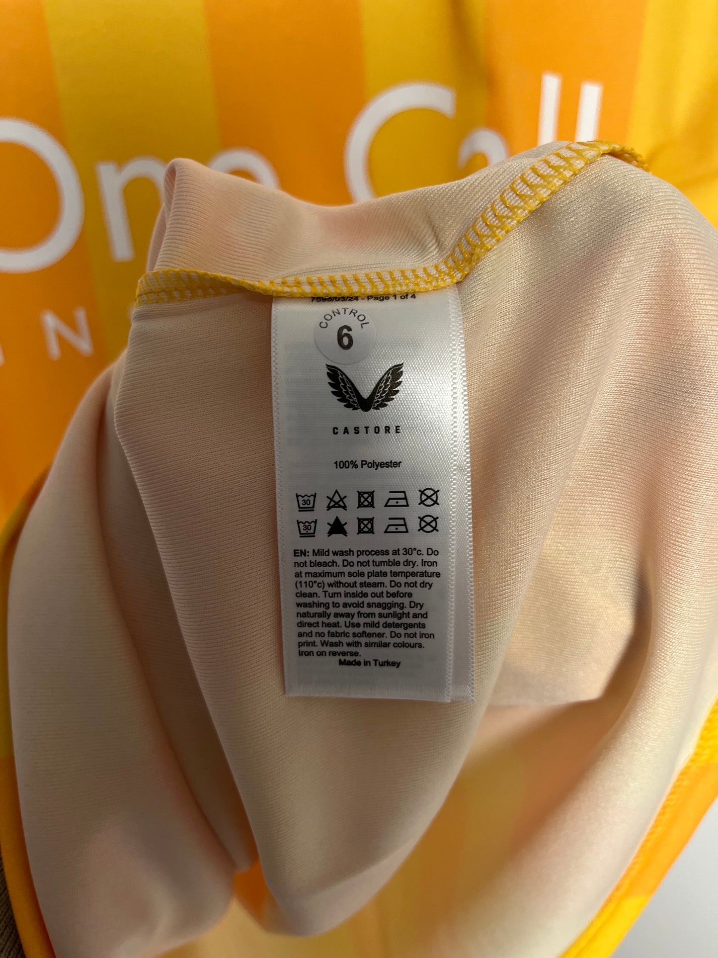 Close-up of a beige garment with a label on a yellow background