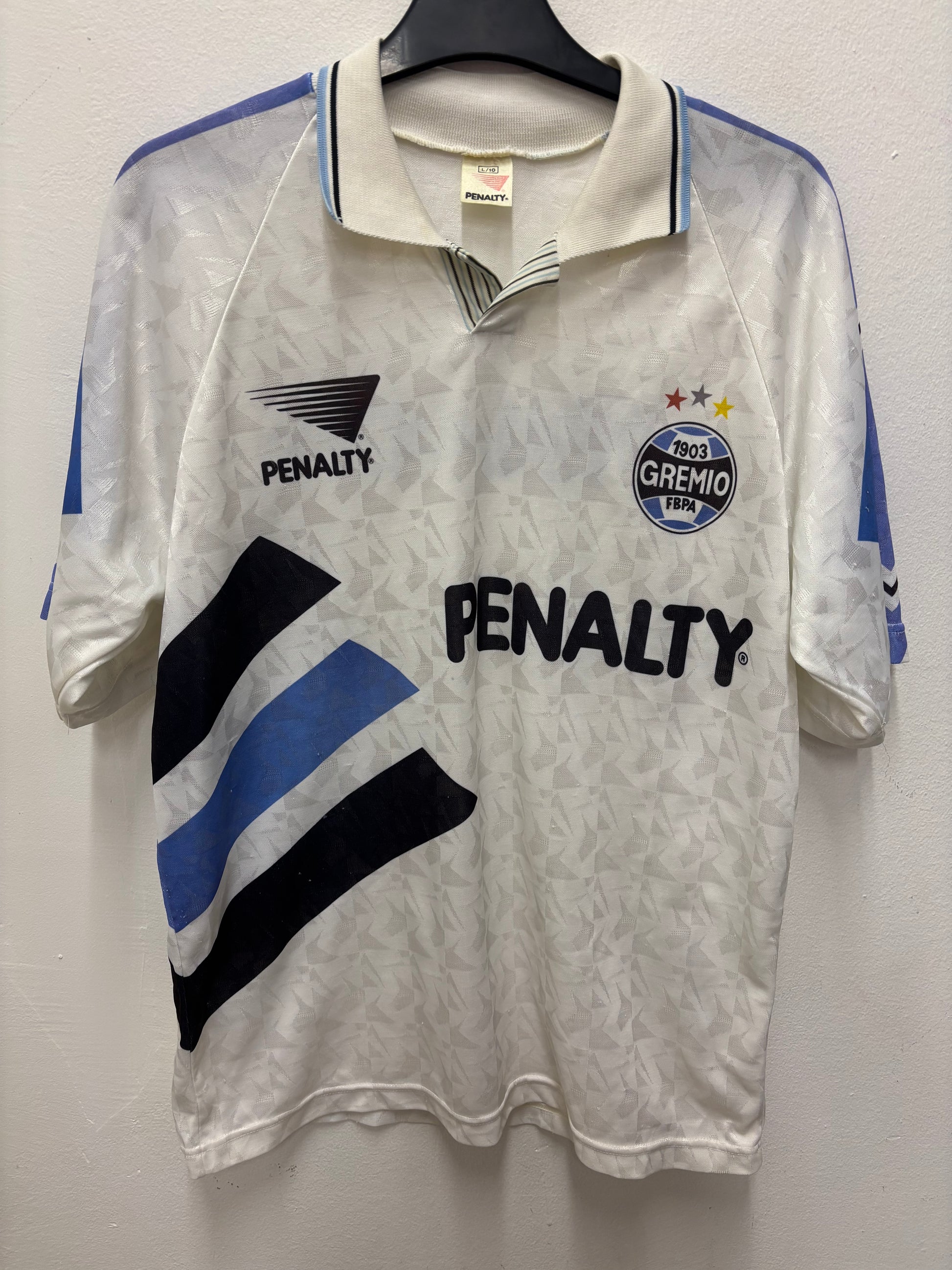 White with blue and black accents, featuring 'Penalty' and 'Gremio' logos on a white background.