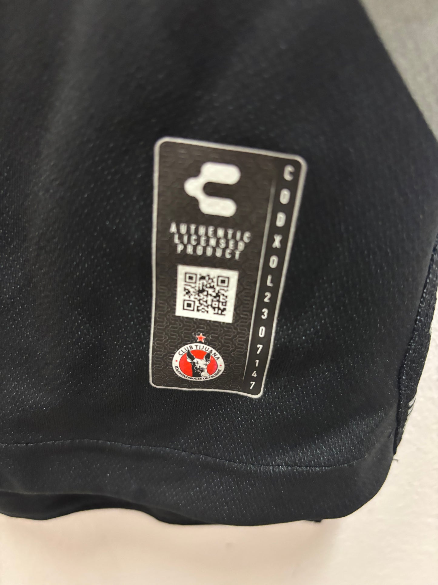 Close-up of a Club Tijuana fotballdrakt with a brand label featuring a logo and tex