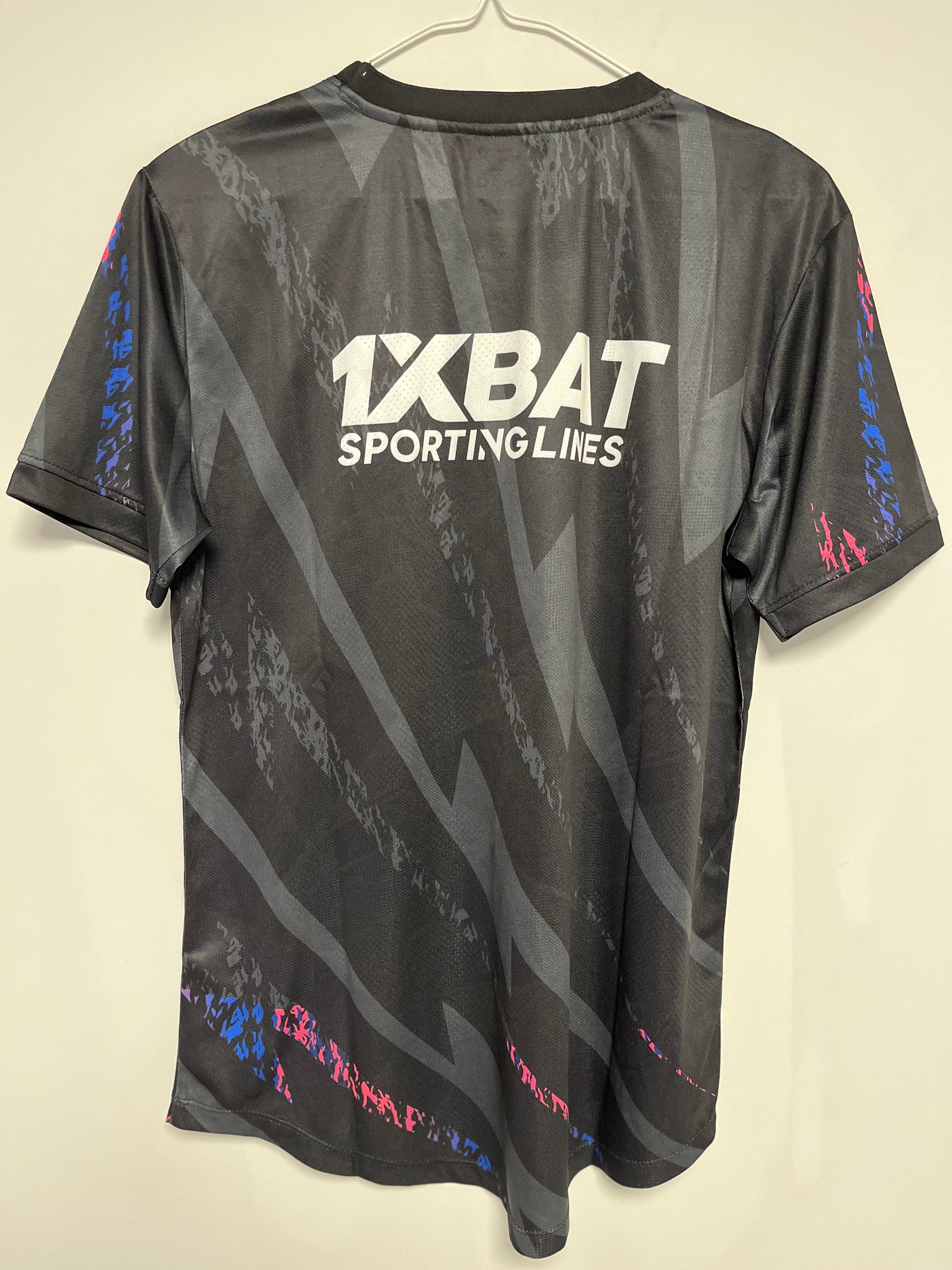 Black sports jersey with '1XBAT Sporting Lines' logo on a beige background