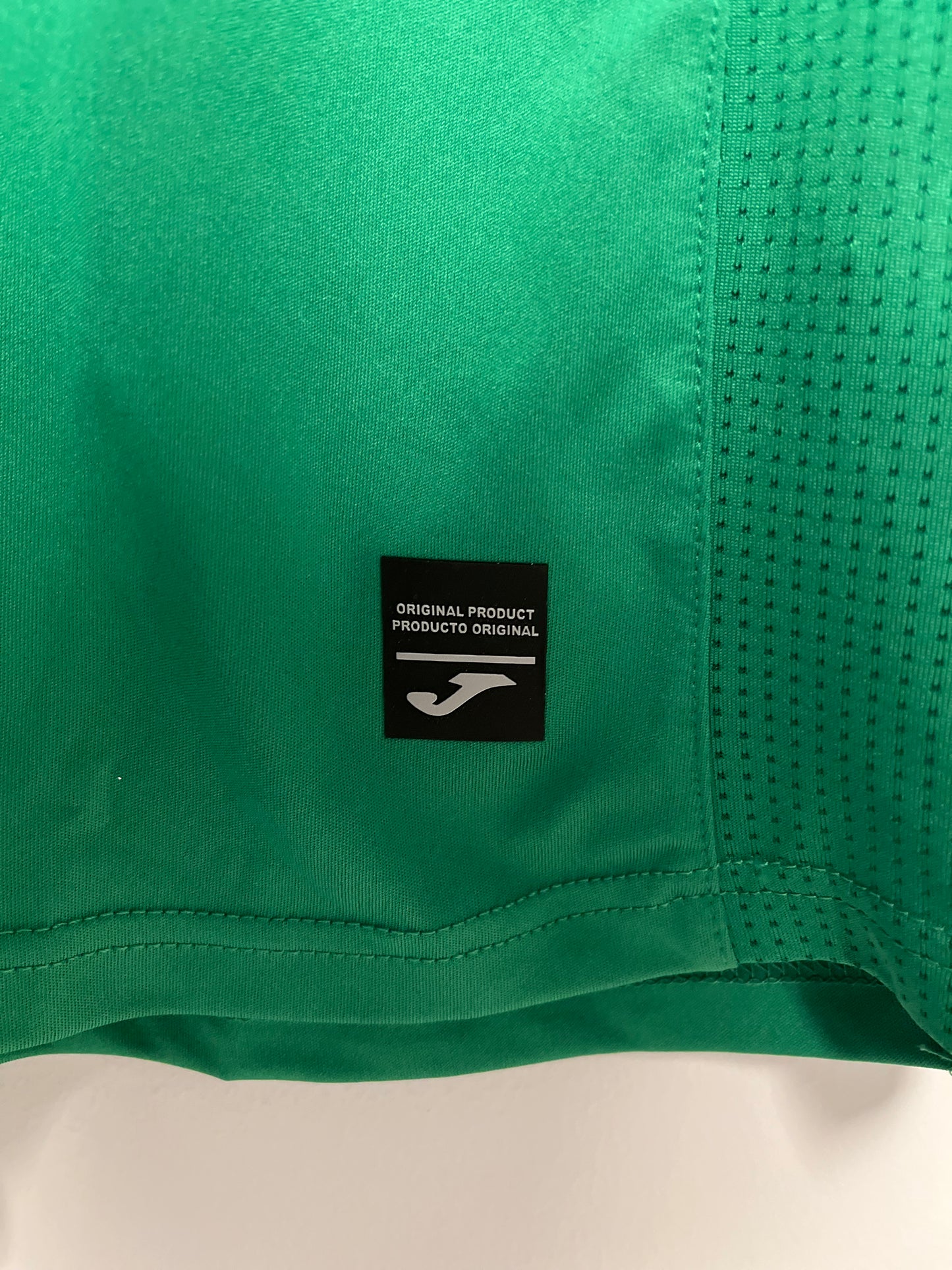 Green athletic shorts with a brand label on a beige background