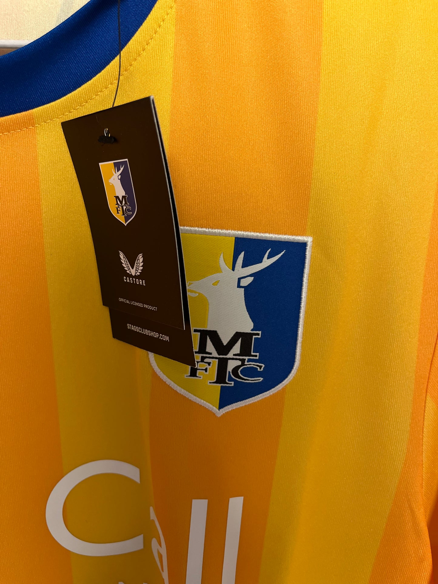Close-up of a football mftc jersey with a brand label on a yellow background
