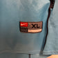 Light blue nike shirt  with a size label indicating 'XL' on a beige background
