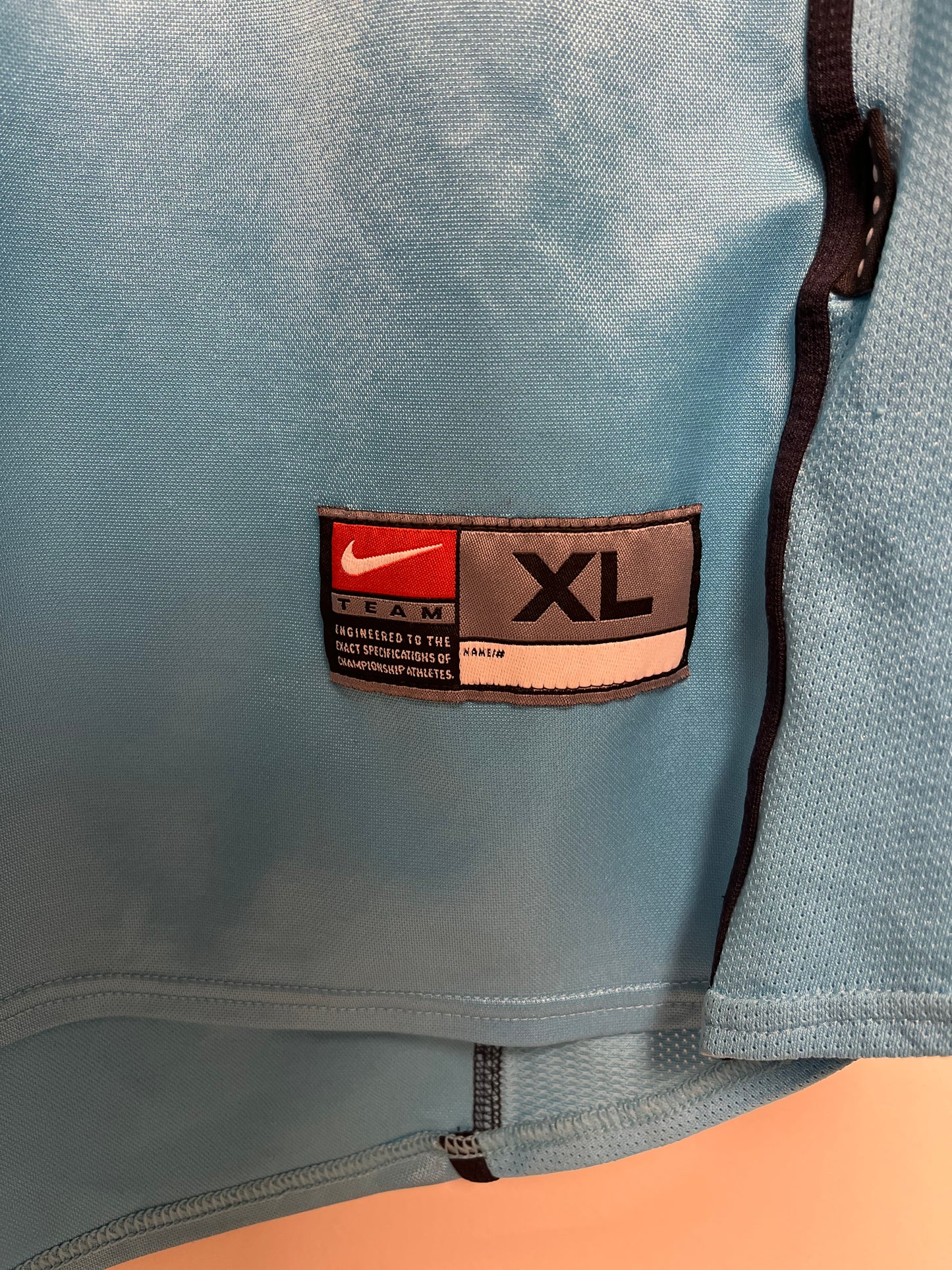 Light blue nike shirt  with a size label indicating 'XL' on a beige background