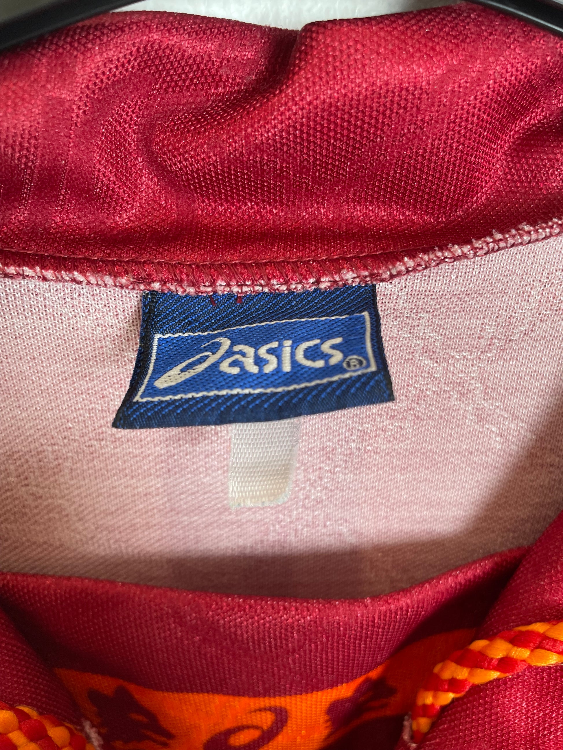 Close-up of a red fabric with an Asics logo tag.