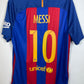 Back view of a blue and red striped FC Barcelona soccer jersey with 'MESSI 10' printed in yellow, hanging on a black hanger against a white wall.