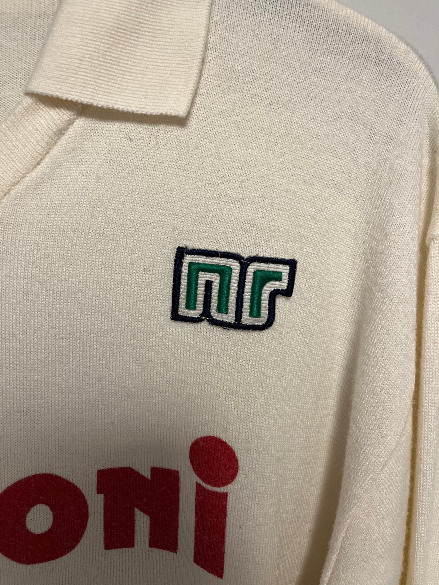 Close-up of a beige fabric with a green and white Nr Shirt  on the left and red text on the right.