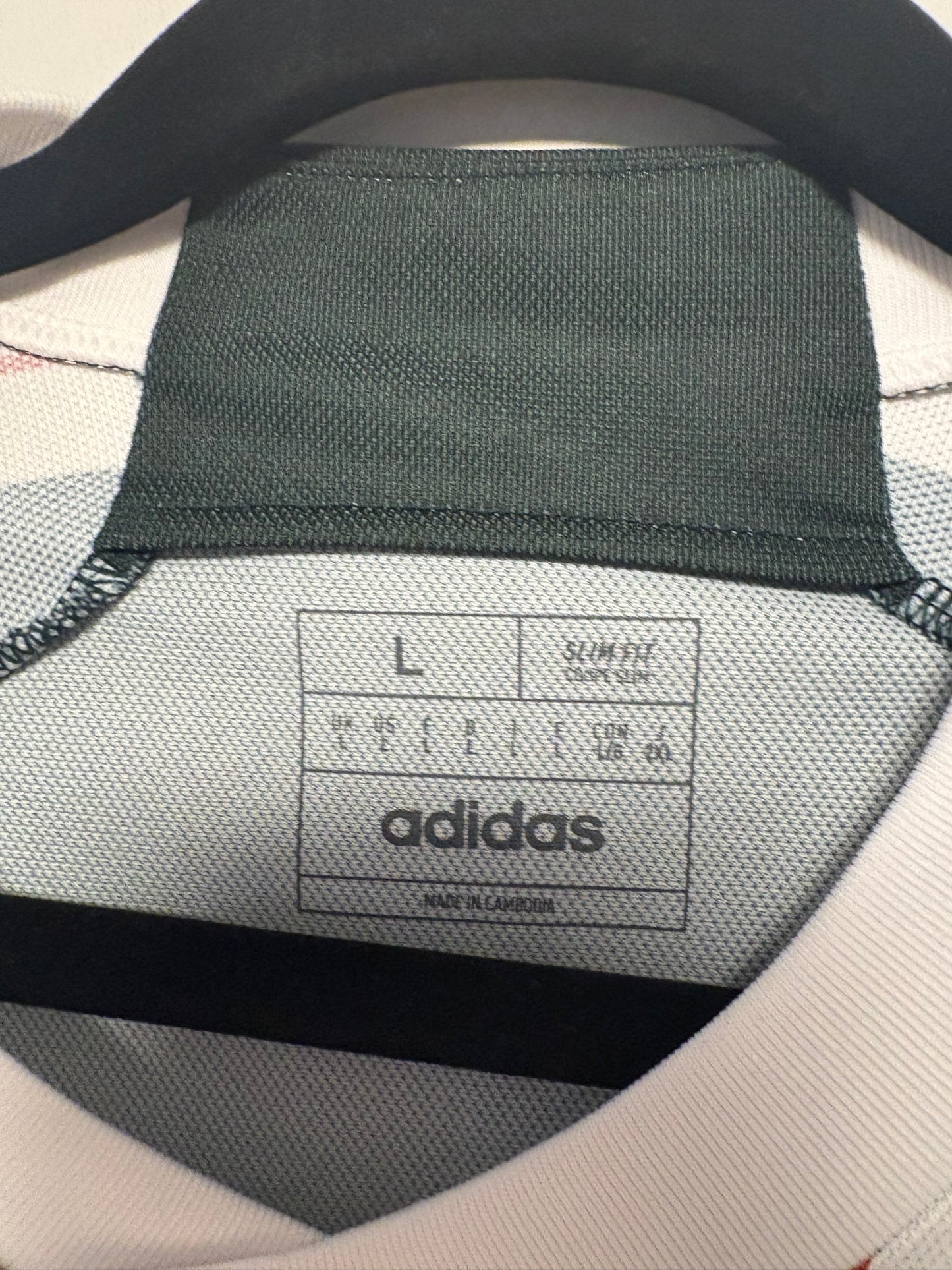 Close-up of Adidas logo and Manchester United club badge on 2023/24 away shirt