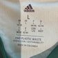 Close-up of an Adidas label on a product with sustainability text.