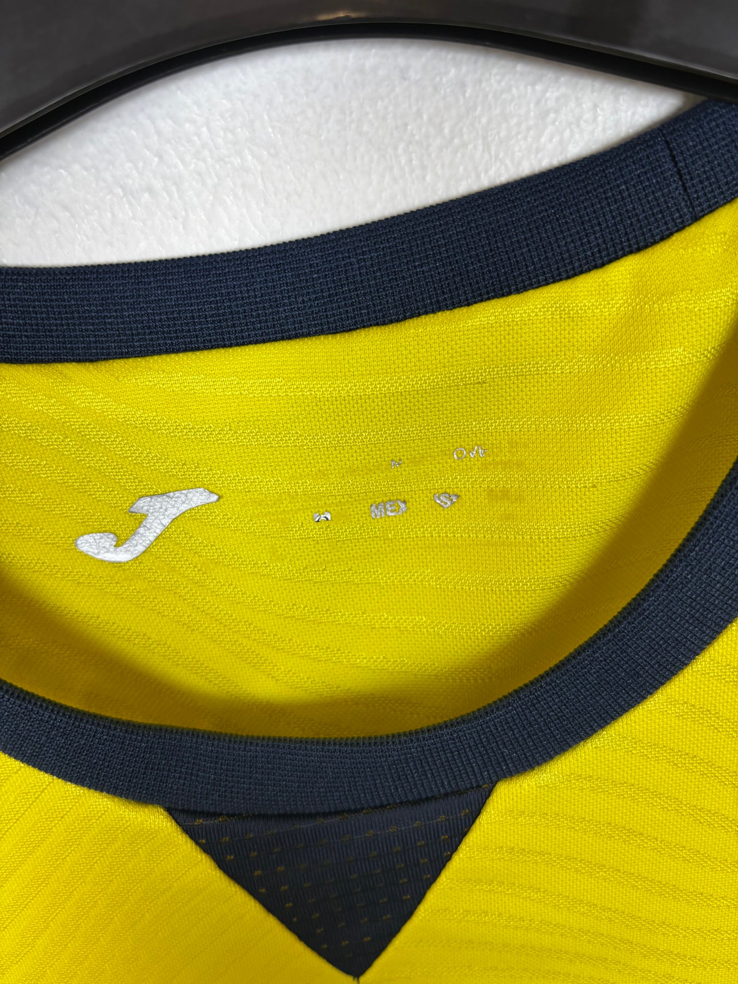 Close-up of Joma logo and Villarreal club badge on yellow 23/24 home shirt with R. Albiol 3
