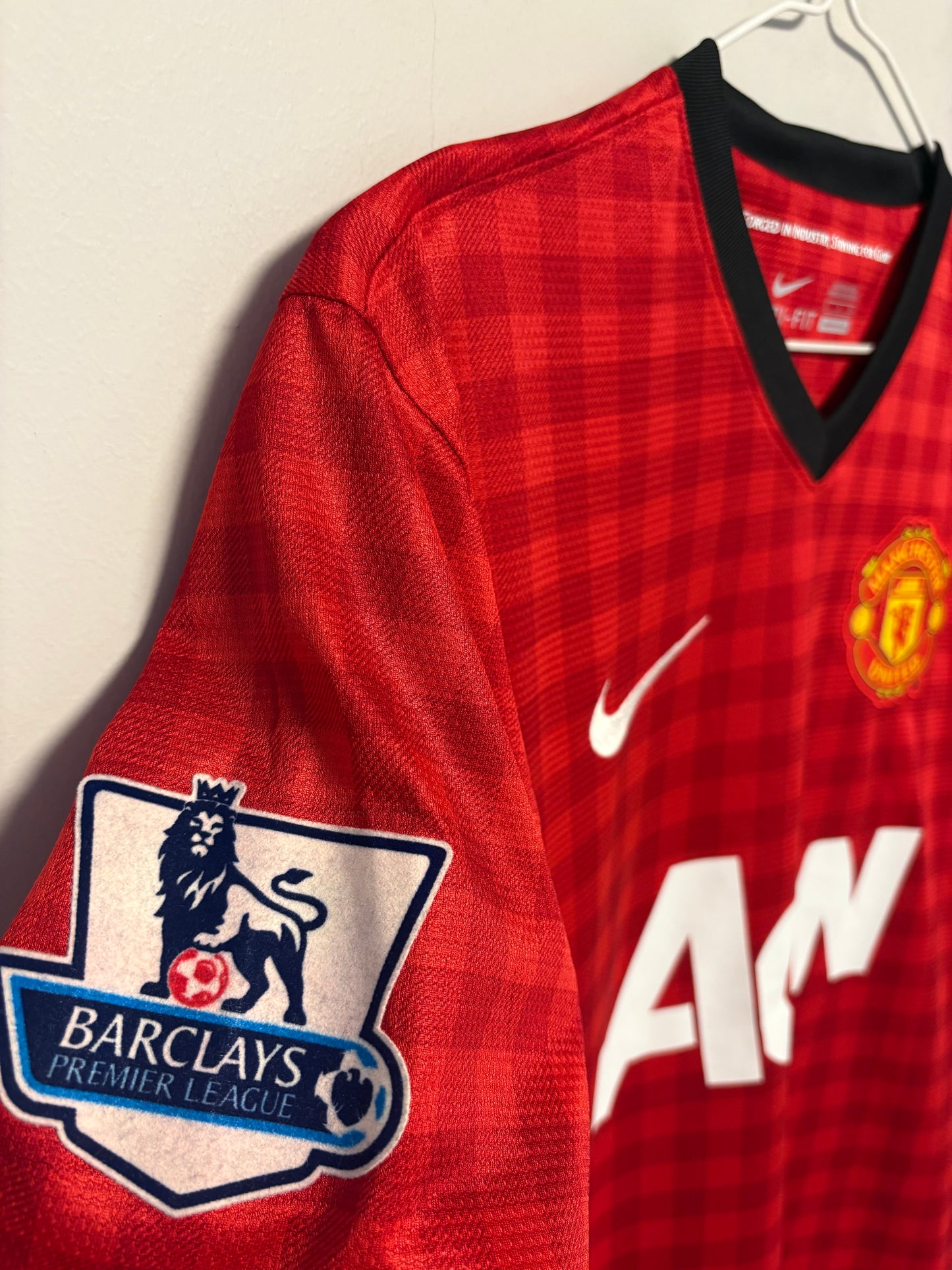 Close-up of Nike swoosh and Manchester United club badge on red 12/13 home shirt