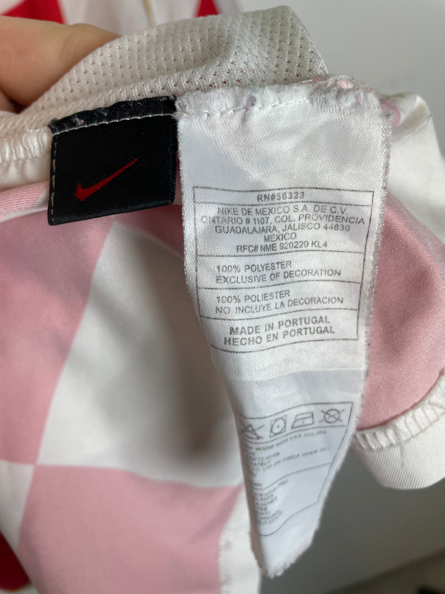 Close-up of a Nike label on a white shoe with a pink background