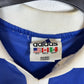Close-up of an Adidas label on a blue and white sports jersey.
