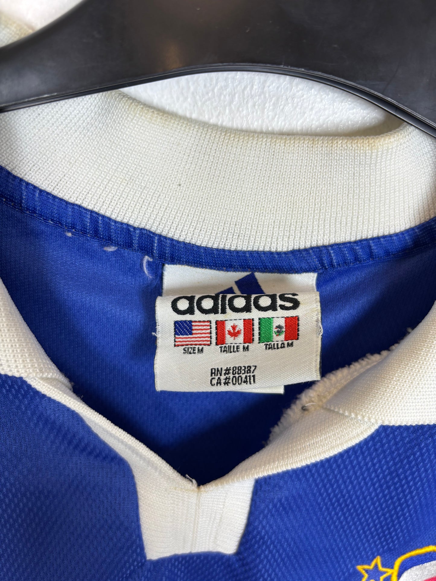 Close-up of an Adidas label on a blue and white sports jersey.