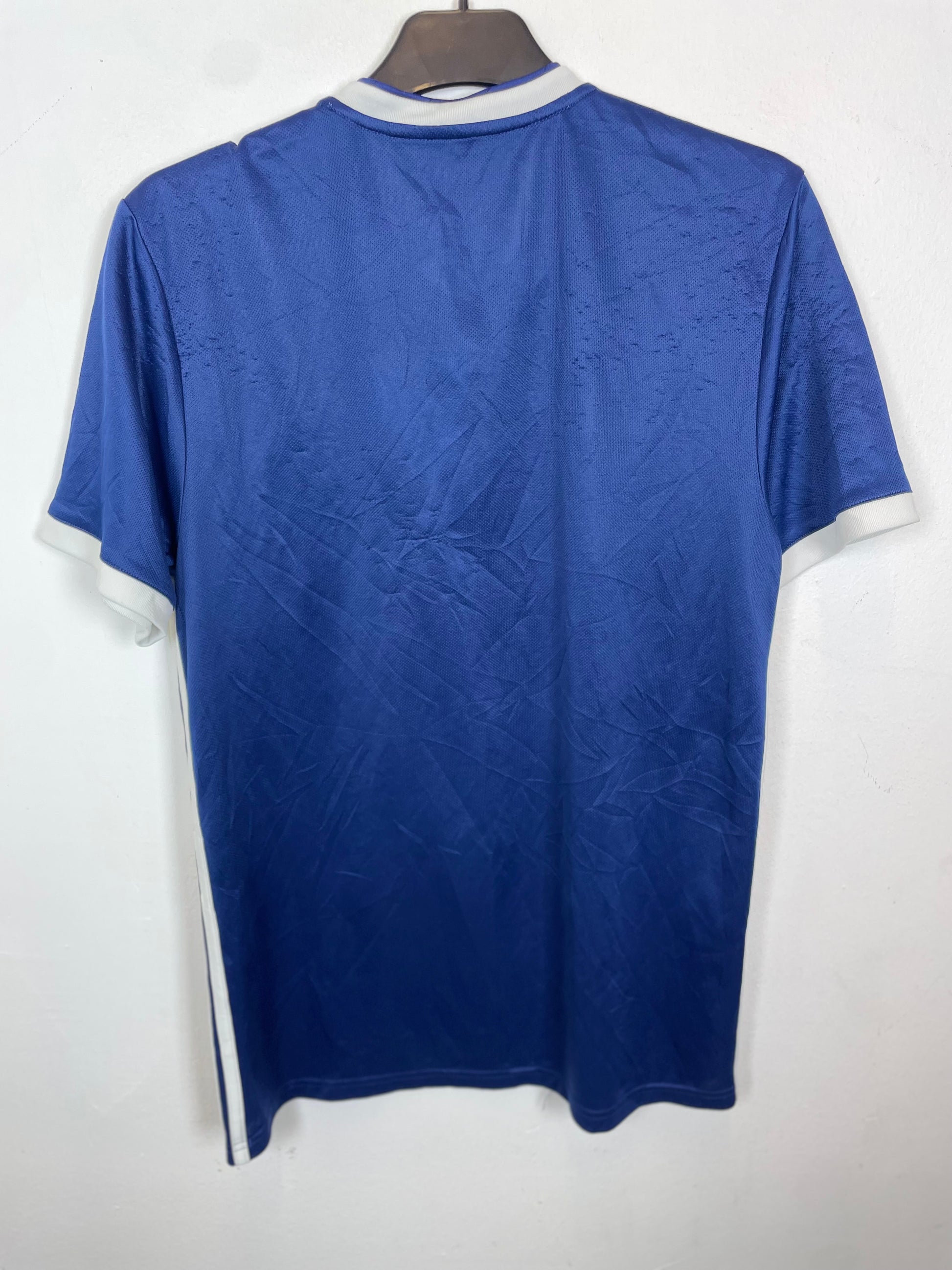 Blue national team jersey with white trim on a hanger against a white background