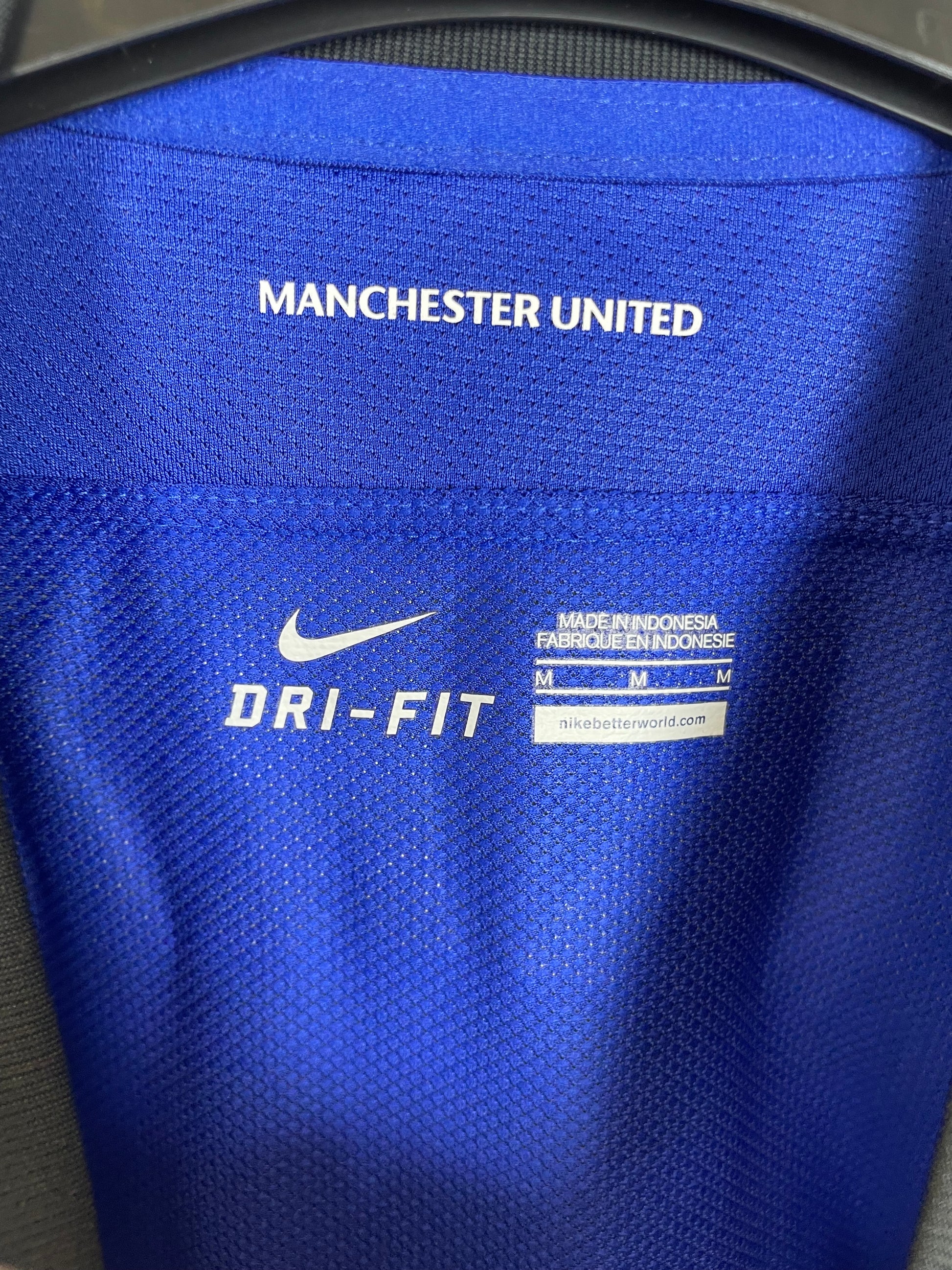 Close-up of Manchester United club badge on Nike 2011-13 away shirt showing red devil crest detail