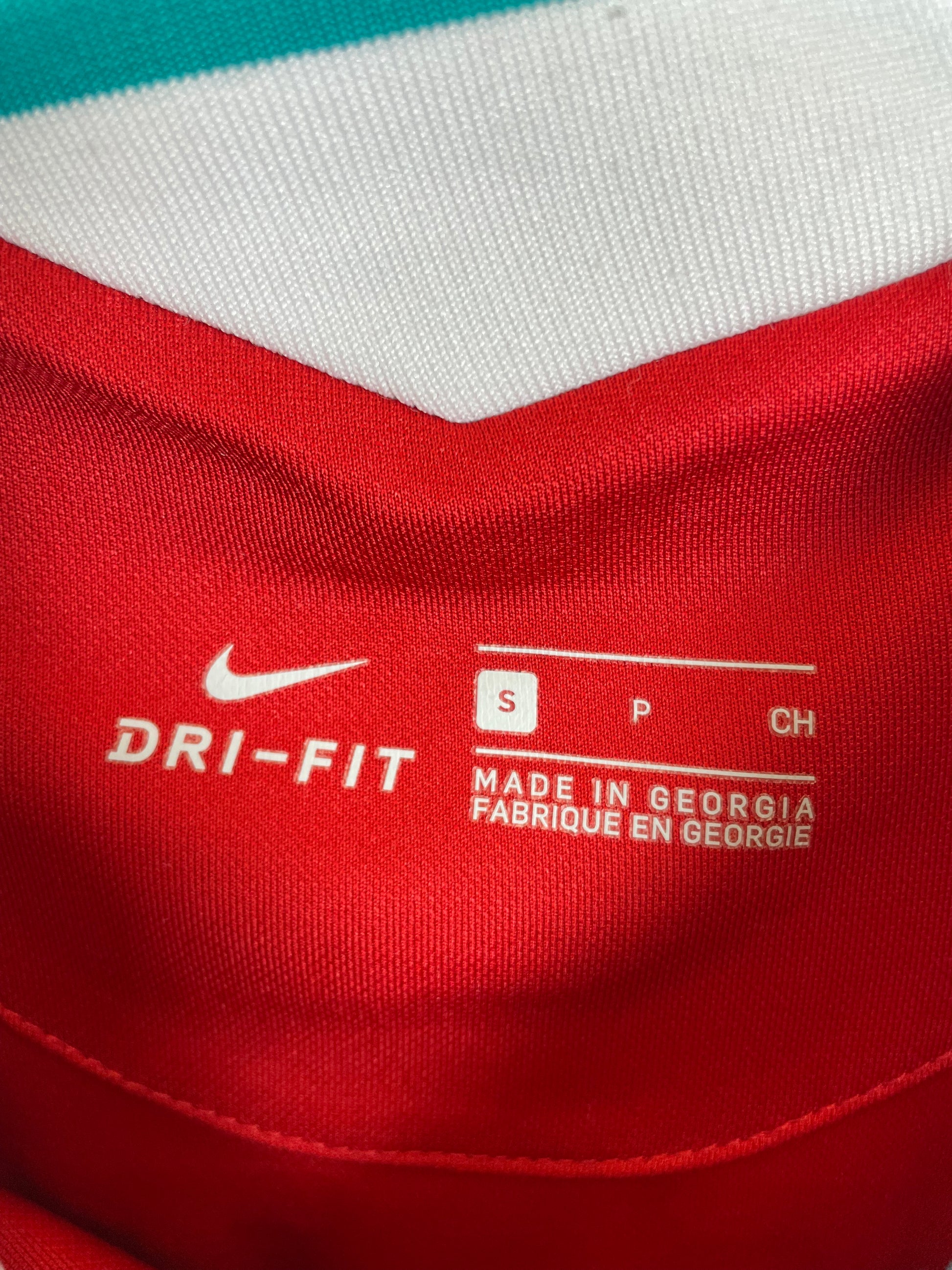 Close-up of a red athletic jersey showing the white Nike swoosh and DRI-FIT text inside the collar, along with size information.