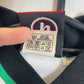 Close-up of the Rochdale AFC club crest and Uhlsport logo on the kids home football shirt, shown in close detail