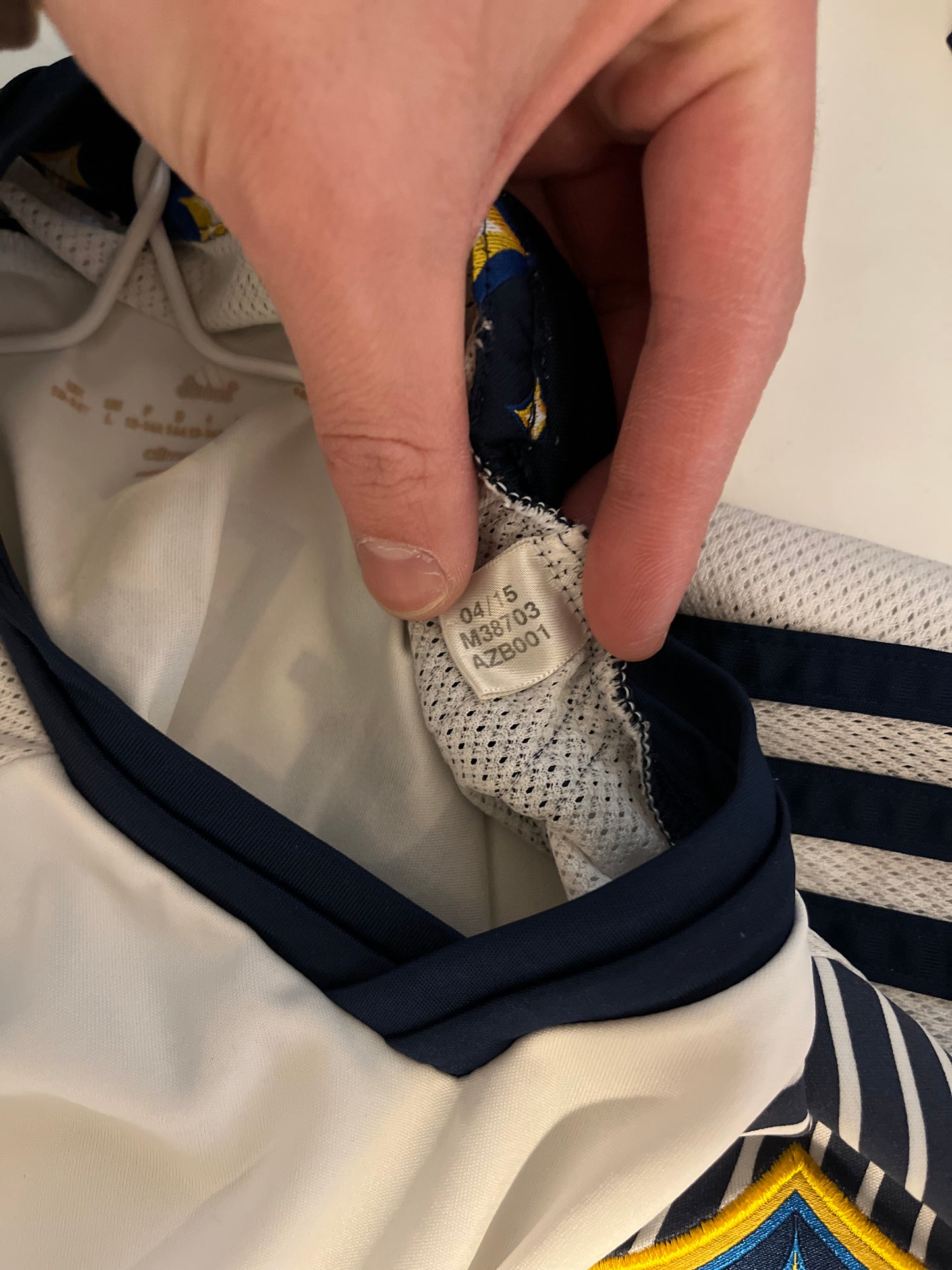 Close-up of a hand holding a sports jersey with a brand label.