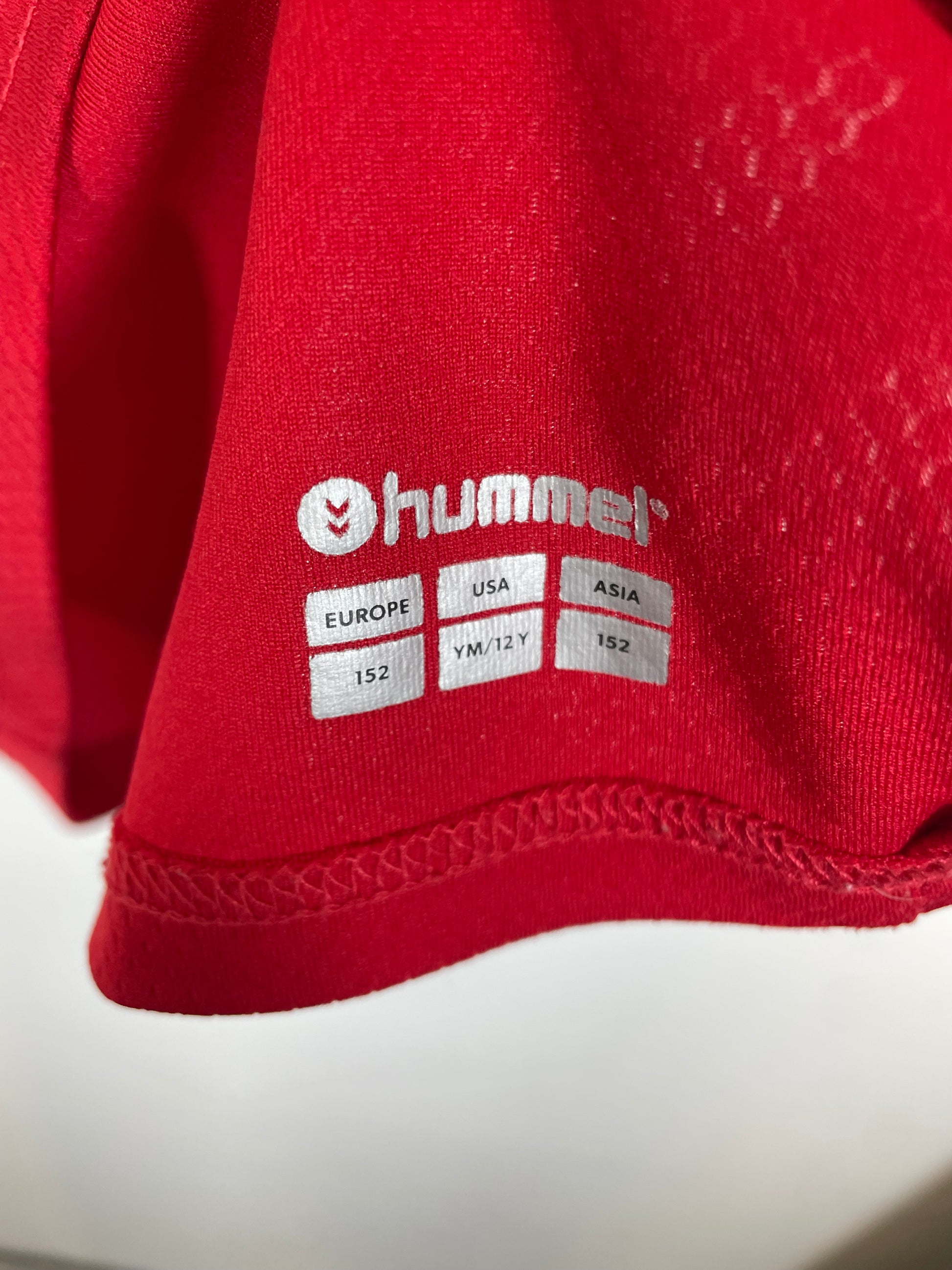 Close-up of Hummel logo and Denmark national team badge on red and white 22/23 home shirt