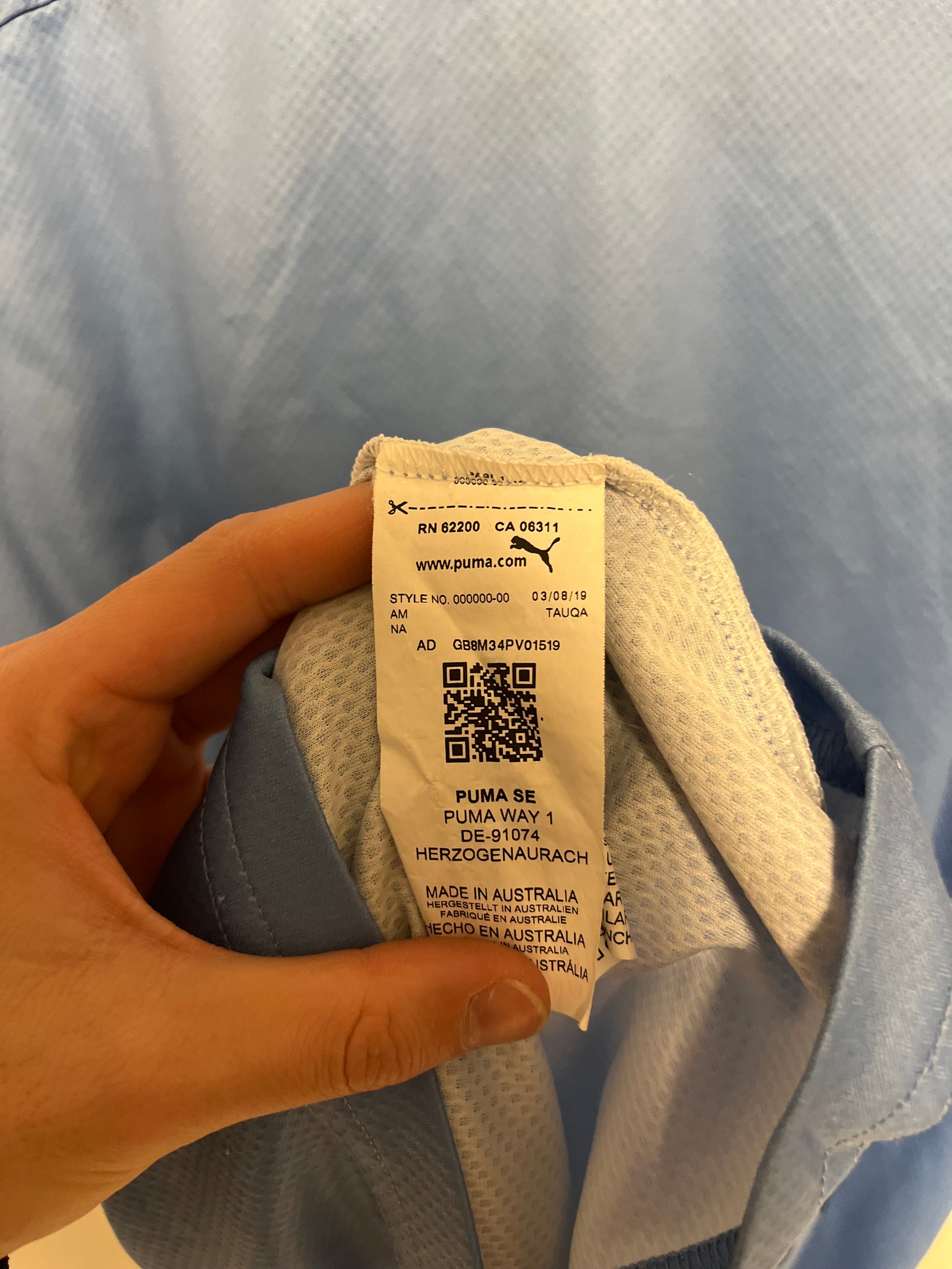 Hand holding a shoe with a tag on a gray surface