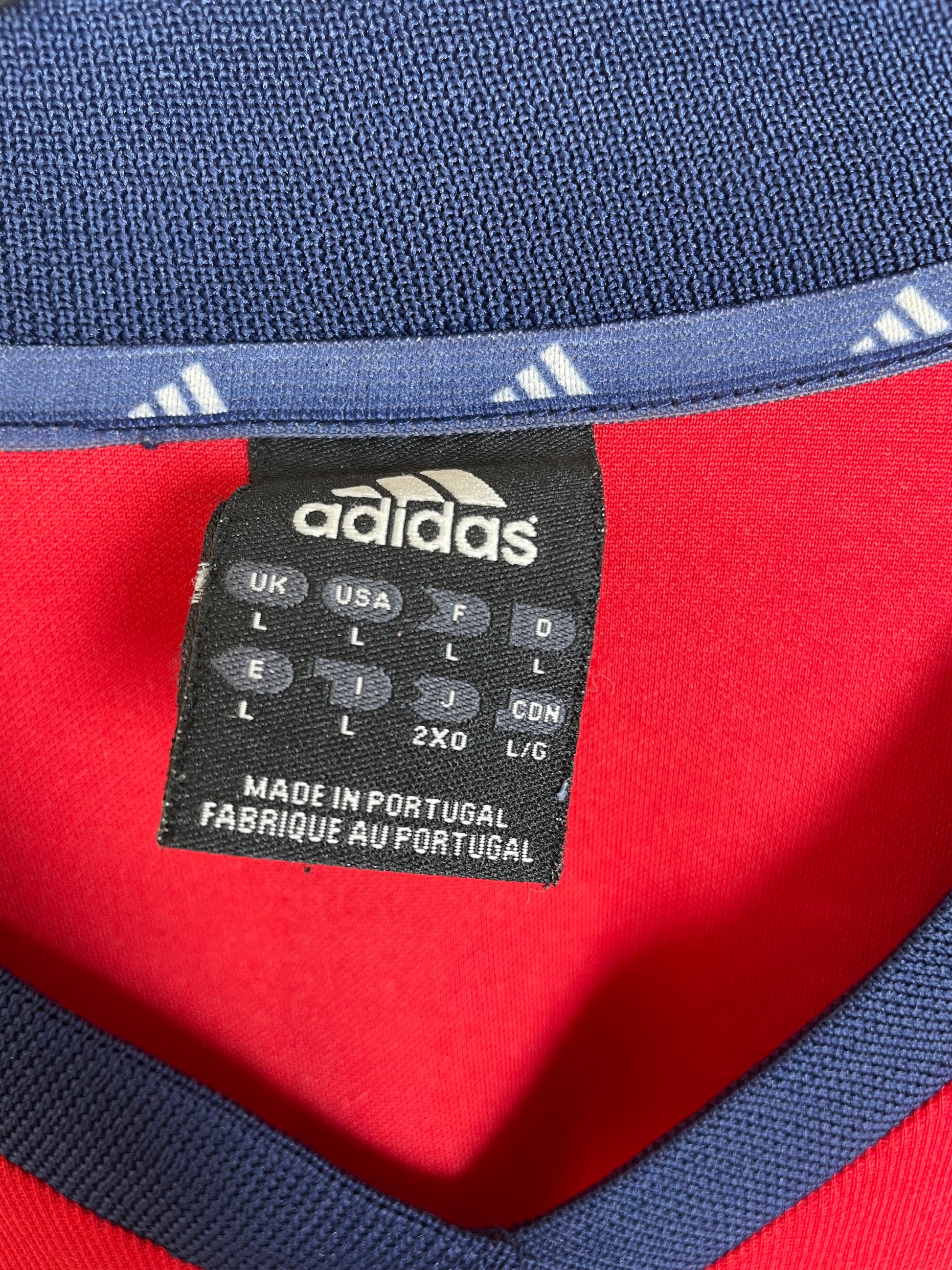 Close-up of Adidas logo and Bayern Munich club badge on 02/03 red home shirt