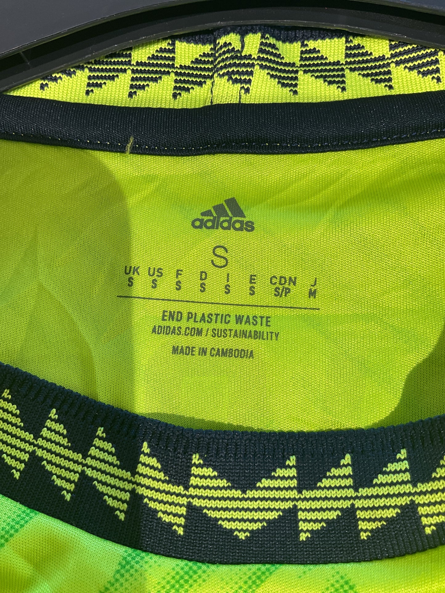 Close-up of a green Adidas bag with text and pattern details.