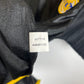Close-up of a black Real Madrid soccer jersey showing the white sewn-in size tag with printed numbers and the club's embroidered crest on the chest.