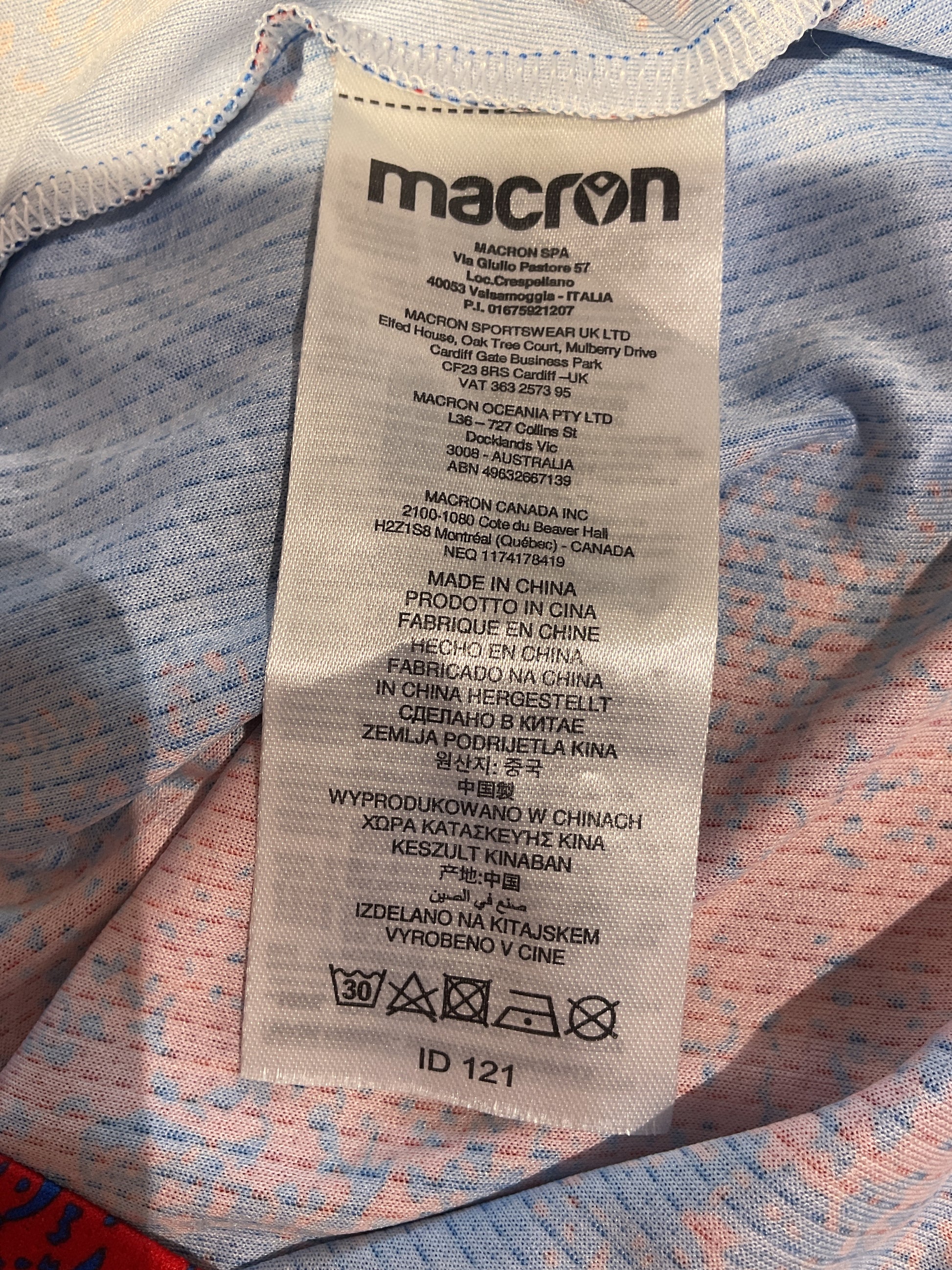 Close-up of a Macron label on on shirt with text and symbols.