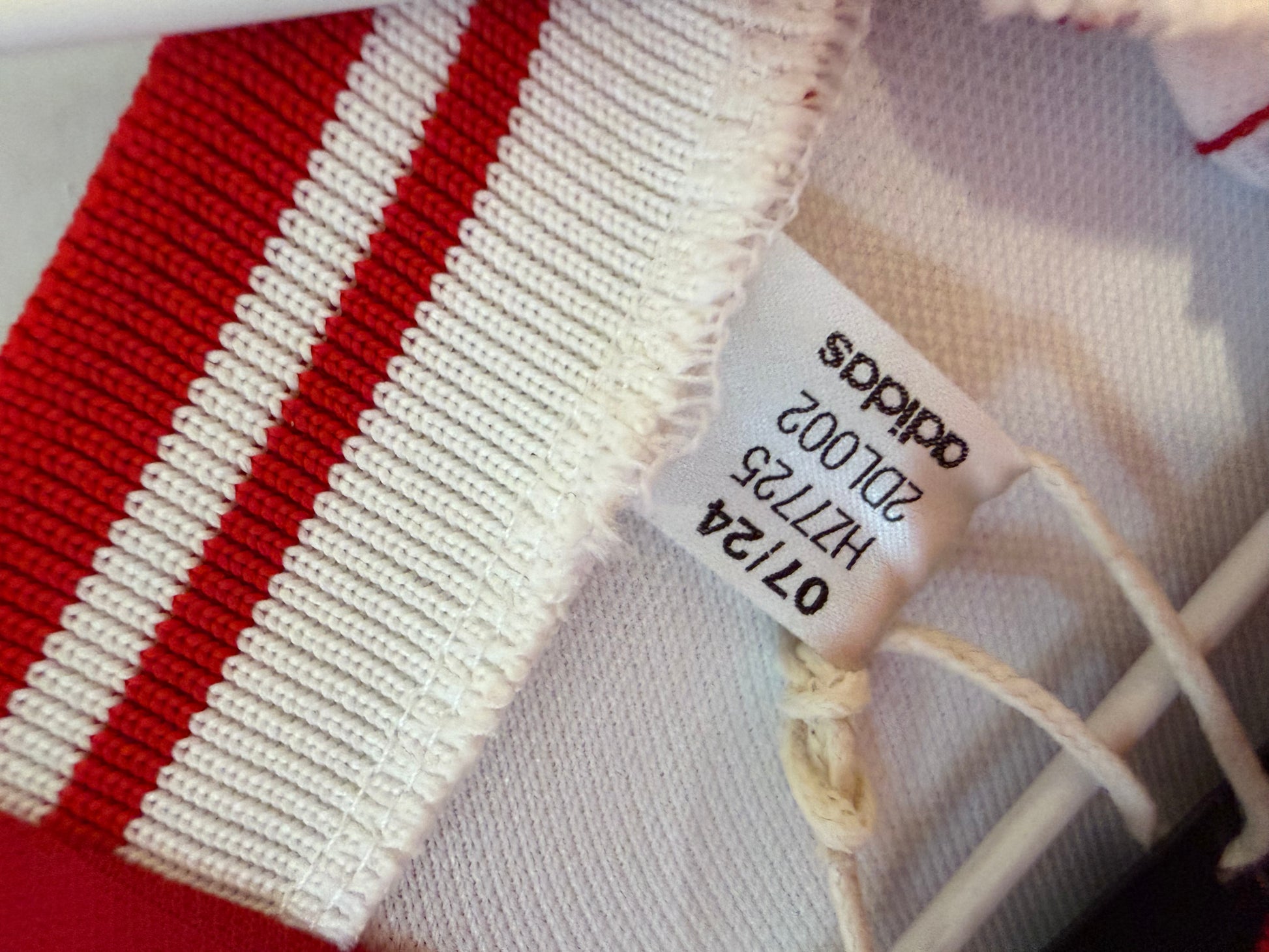 Close-up of Ajax Amsterdam club badge and Adidas three stripes logo on white 2023/24 home jersey