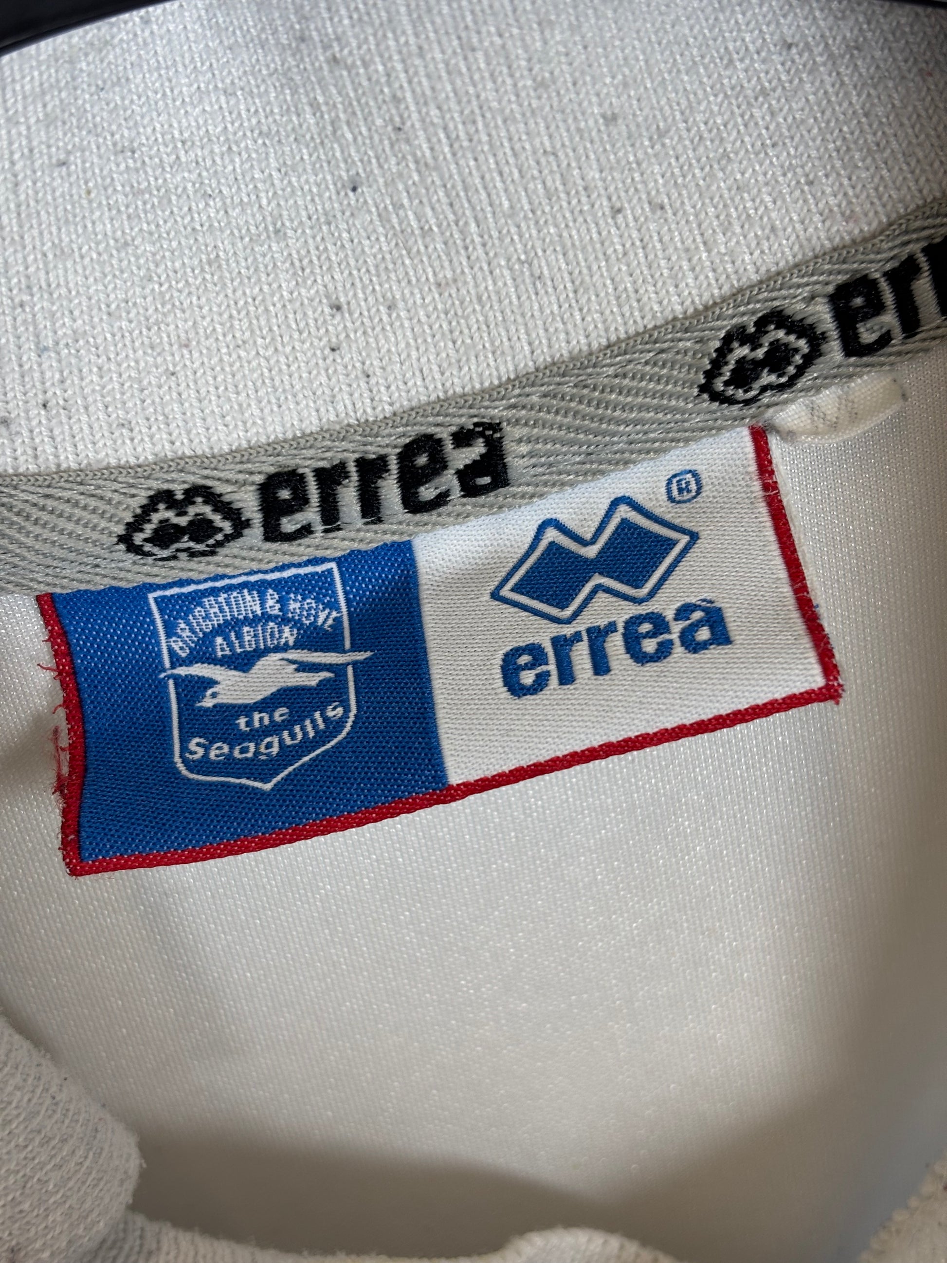Close-up of Errea logo and Brighton and Hove Albion club badge on 2004/06 home shirt