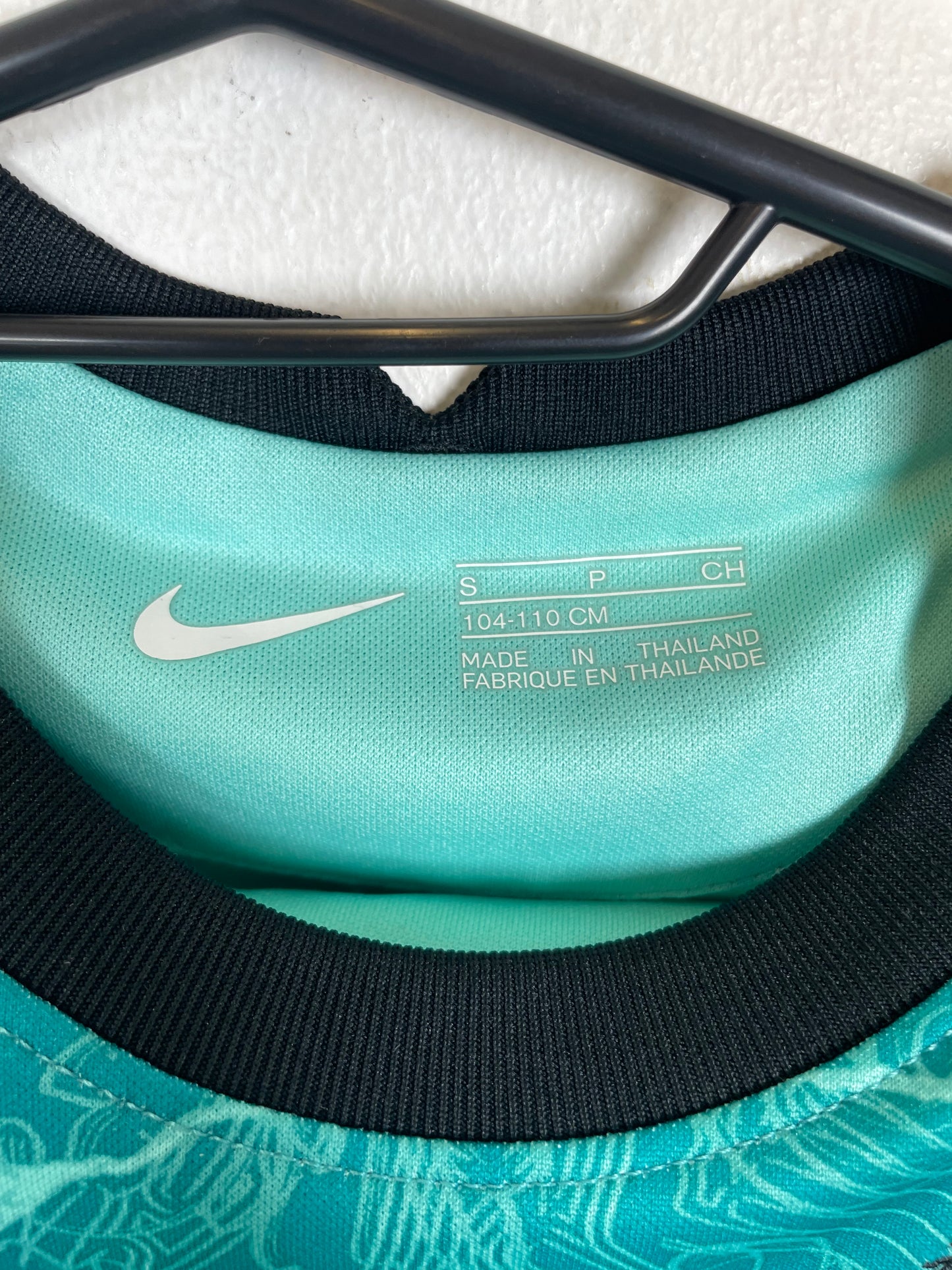 Close-up of Liverpool FC crest and Nike Swoosh logo on teal 2020/21 away kit