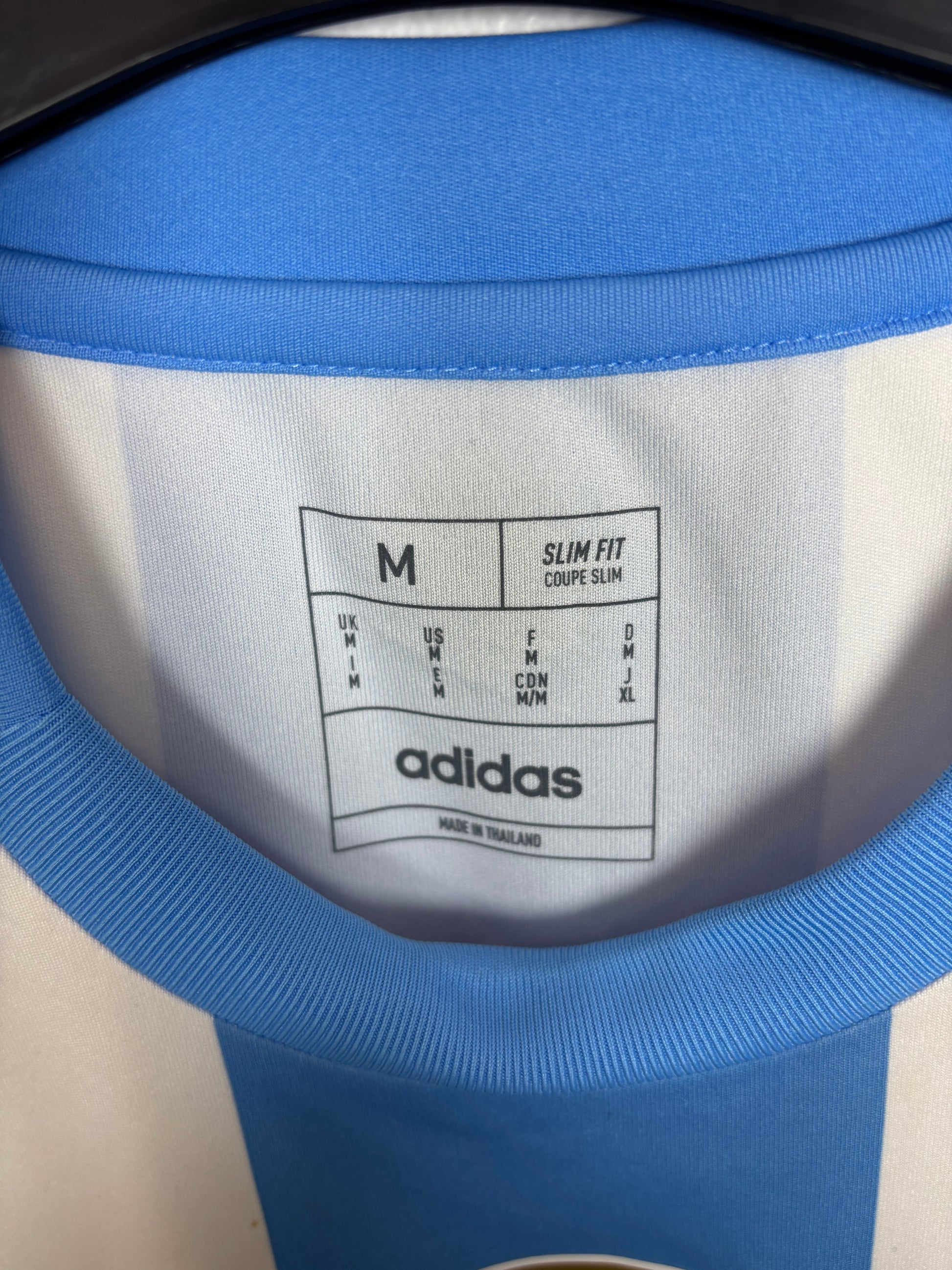Close-up of Adidas logo and Argentina club badge on light blue home shirt with Messi 10