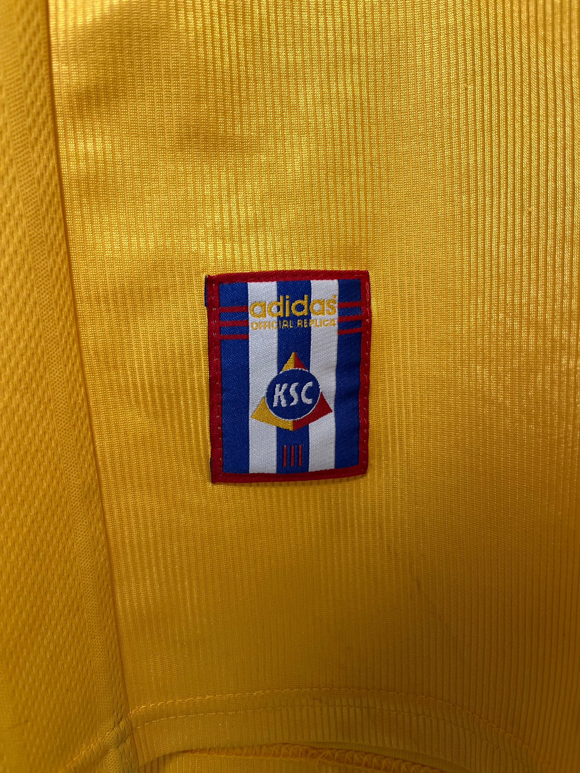 Close-up of an Adidas logo on a yellow textured fabric background