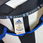 Close-up of Adidas logo and Newcastle United club badge on 2000/01 home shirt