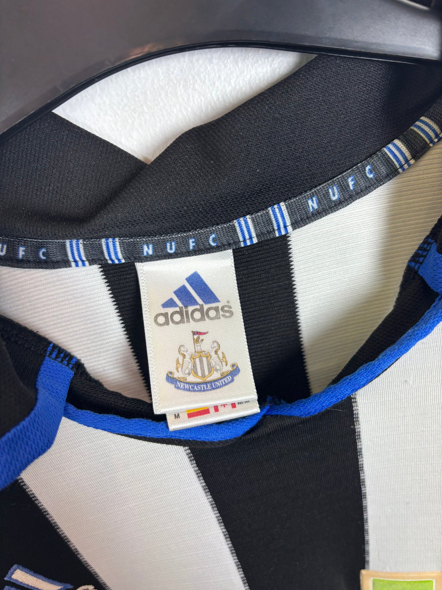 Close-up of Adidas logo and Newcastle United club badge on 2000/01 home shirt