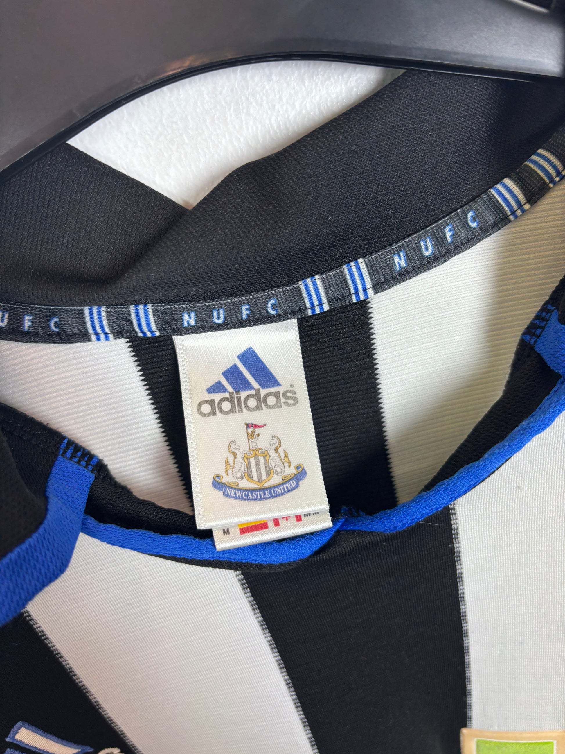 Close-up of Adidas logo and Newcastle United club badge on 2000/01 home shirt